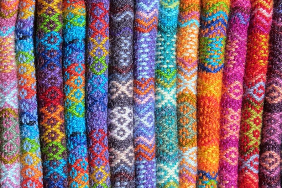 Rolls of patterned fabric stacked on a shelf.