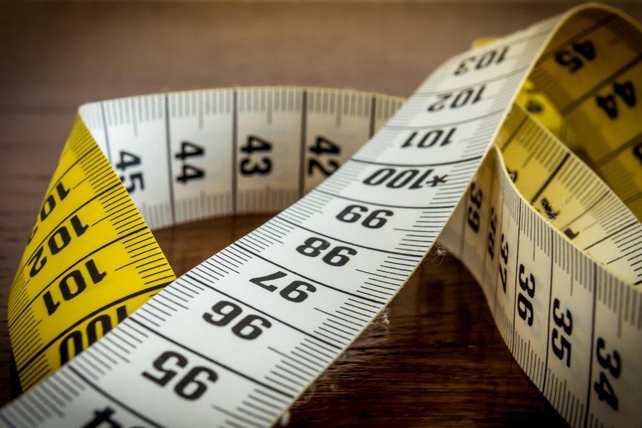 A yellow measuring tape coiled on a pale surface.