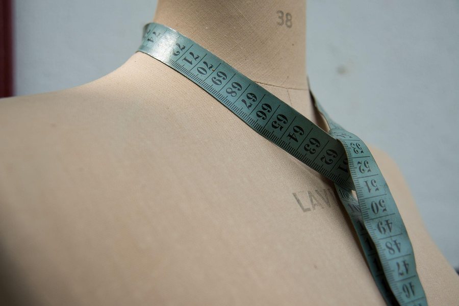 A dress form with a tape measure across the shoulder.