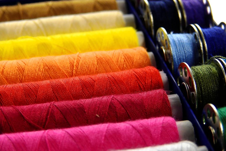 Rolls of coloured fabric on a shelf.