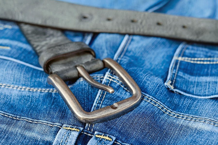 A leather belt threaded through denim belt loops.