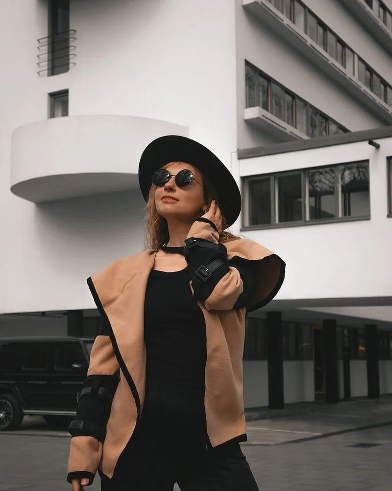 A camel coat worn open over a dark base layer.