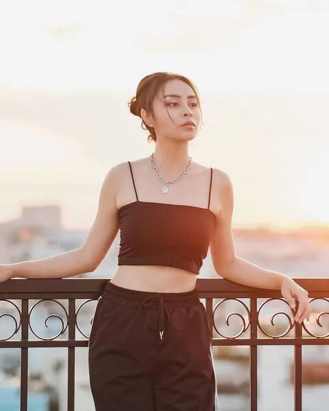 A woman in a dark outfit at sunset.