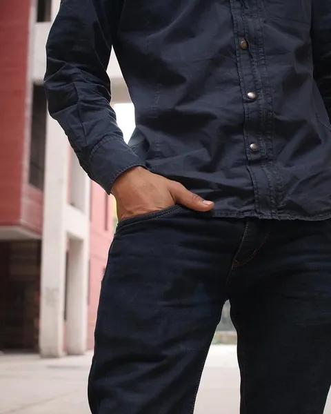 A man in a dark linen shirt standing in a doorway.