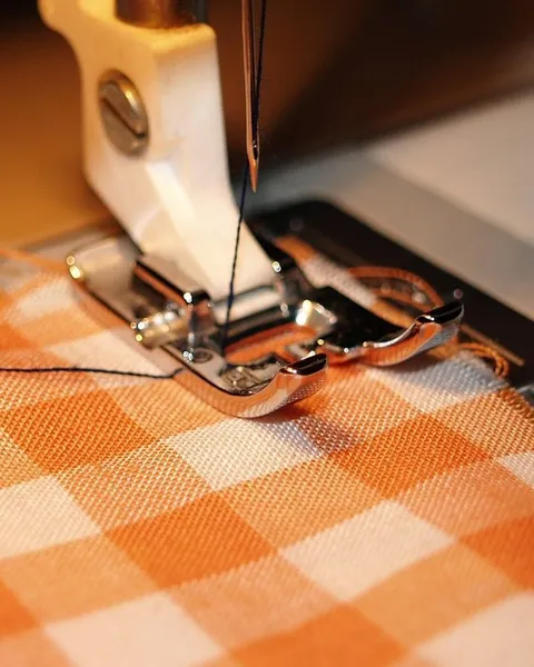 A sewing machine stitching checked fabric.