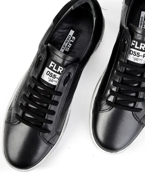 Black leather sneakers photographed on a white surface.