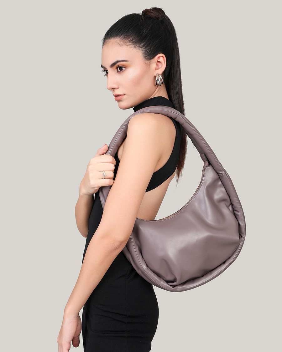 A woman carrying a grey leather shoulder bag.