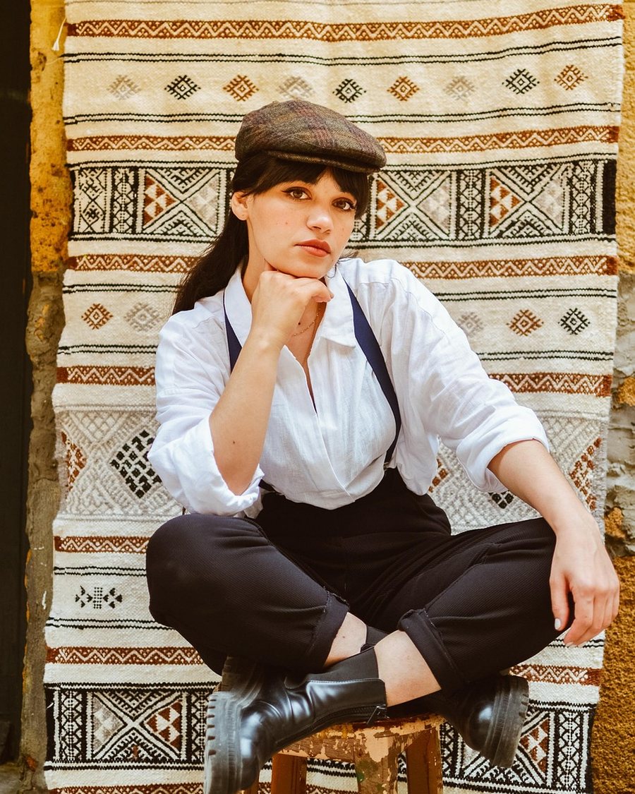 A person in a striped shirt seated on a patterned rug.
